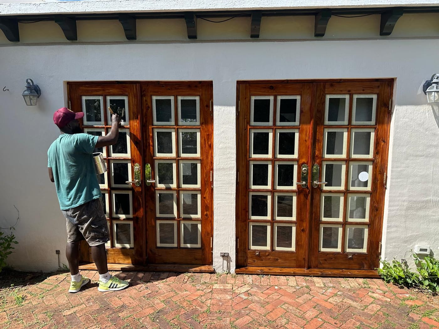 T&H Painting crew brushing stain onto cedar French doors